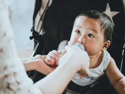 person feeding baby from feeding bottle